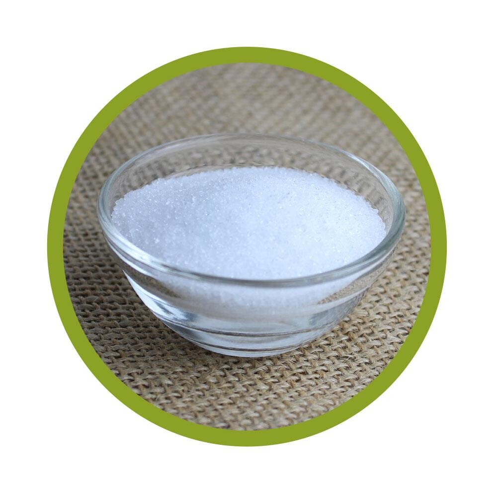 Cristaux blancs de xylitol dans un bol en verre sur un tissu naturel.