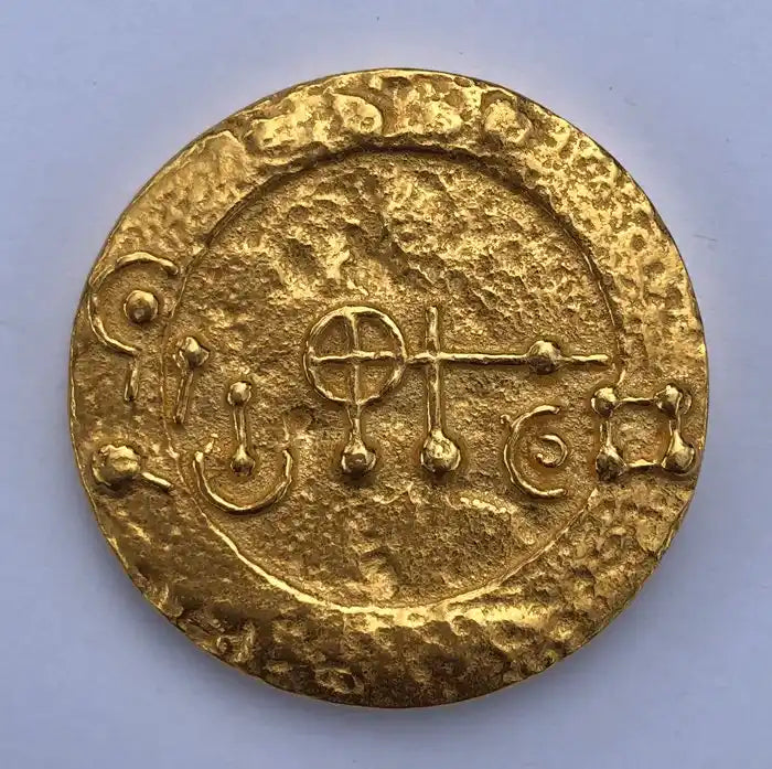 A-Medaillon: rundes goldfarbenes Medaillon mit eingeprägten Symbolen.